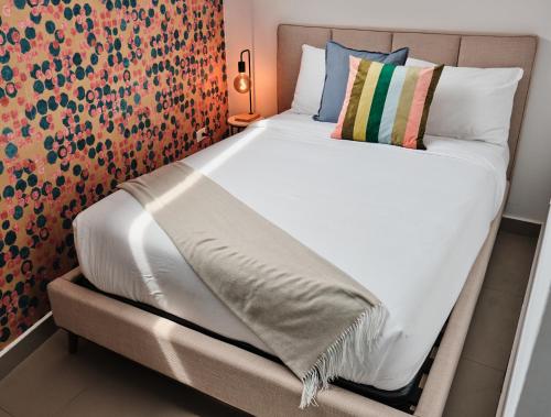圣胡安La Calma Poshtel的一张带白色床单和枕头的床