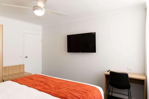 米尔迪拉伊克诺米尔迪拉旅舍的一间卧室配有一张床和一张书桌,墙上配有电视。