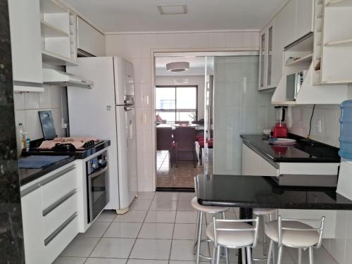 瓜拉派瑞Apartamento na Praia do Morro -160 metros da praia -Ar condicionado e internet -Perto de tudo的厨房配有白色家电和白色橱柜