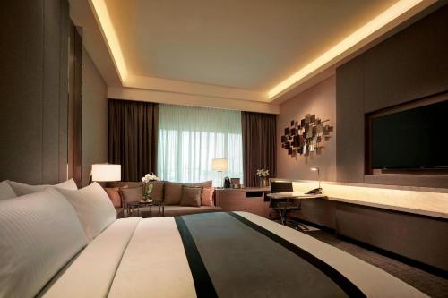 吉隆坡JW Marriott Kuala Lumpur的酒店客房,配有床和电视