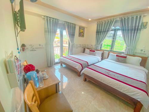 惹岛KHÁCH SẠN HƯNG THỊNH - Lý Sơn的一间卧室设有两张床、一张桌子和窗户。