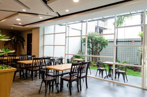 美娜多Arcadia Hotel Manado的餐厅设有桌椅和大窗户。