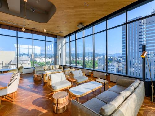 广岛THE KNOT HIROSHIMA的带沙发和椅子的客厅以及大窗户。