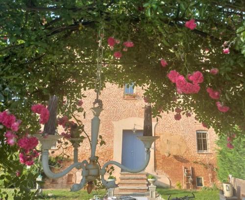 Villanova dʼAstiLa Boheme的一座建筑,有一扇蓝色的门和一些粉红色的玫瑰