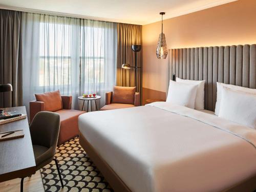 斯图加特斯图加特弗塔纳铂尔曼酒店的酒店客房带一张大床和一把椅子