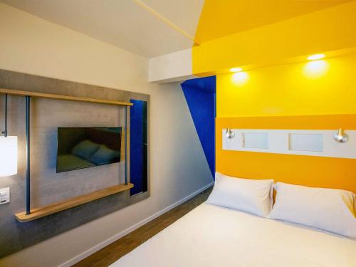 累西腓ibis budget Recife Jaboatão的一间卧室配有一张黄色和蓝色墙壁的床