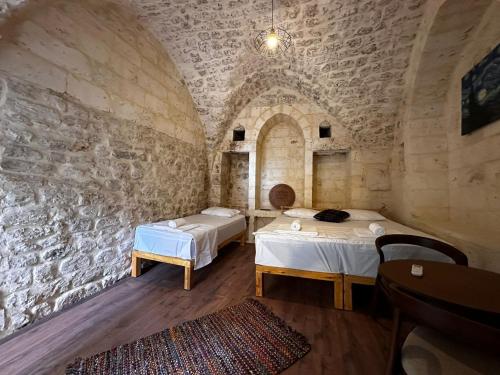 尚勒乌尔法Petra Hotel & Coffee House的一间设有两张床和石墙的房间