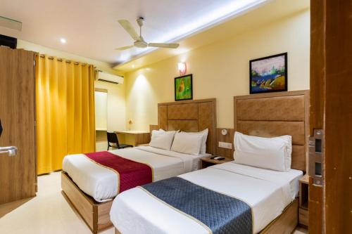 孟买LOTUS GRAND HOTEL MUMBAI的酒店客房设有两张床和一张桌子。