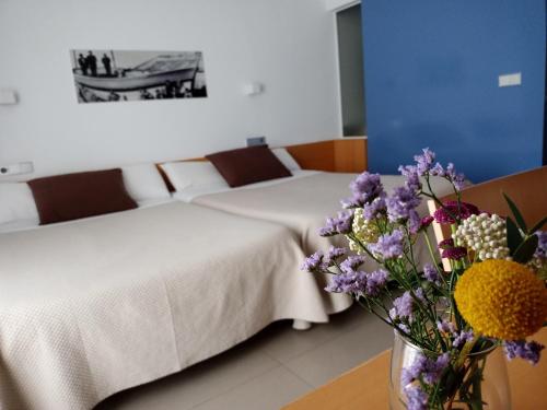 卡沃内拉斯Alboran hotel的酒店客房带两张床和花瓶