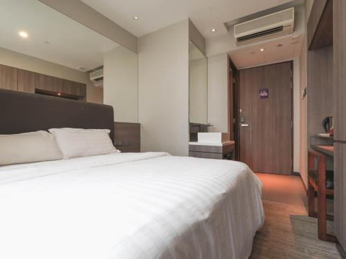 新加坡Amrise Hotel Kitchener, Check In 9PM, Check Out 8AM的一间带白色大床的卧室和一间浴室