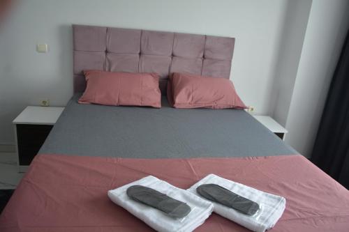 吉拉克Hera Rezidans的一张配有粉红色和灰色床单及粉红色枕头的床