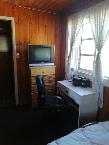 黑岛Habitación individual el amenecer de la Estancia的一间卧室配有书桌、椅子和电视。