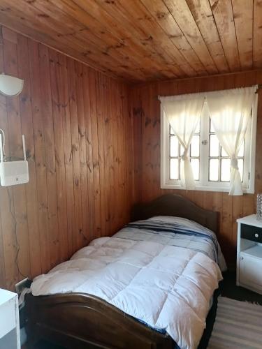 黑岛Habitación individual el amenecer de la Estancia的木墙和窗户的客房内的一张床位