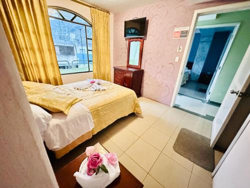 巴尼奥斯Hostal Grand Rio的一间卧室配有一张床和一张鲜花桌子