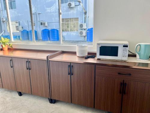 斗湖Theresa's Homestay的一张带微波炉的桌子和一个位于办公室的窗户