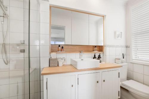 纽波特La Mer的白色的浴室设有水槽和淋浴。