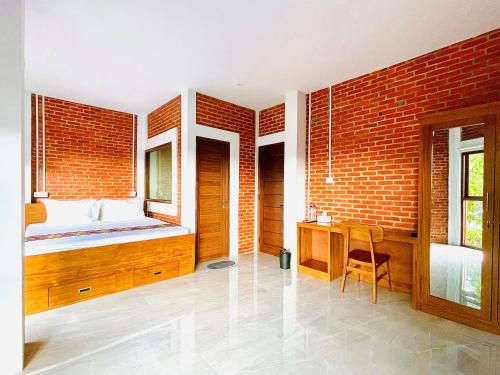 纳闽巴霍Puu Pau Hotel & Coffee Shop的一间卧室配有一张床、一张桌子和砖墙