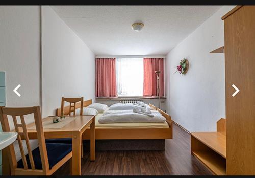 库罗阿尔滕堡奥斯特格比格酒店的一间卧室配有一张床、一张桌子和一个窗户。