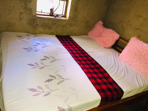 内罗毕Kiharas Farm stay的一张带铺着平铺地毯的床和两个粉红色枕头