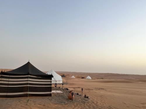 ḨawīyahStarwatching Private Camp的沙漠沙子中的一组帐篷
