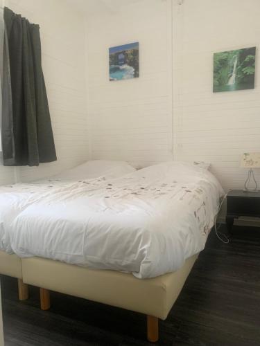 WinsumHet molenhuisje的卧室内的一张白色床,墙上挂着两张照片