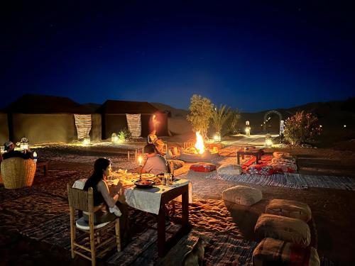 梅尔祖卡Sahara wellness camp的两人坐在火前的桌子上