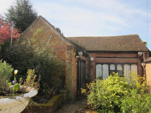 哈特菲尔德Barn conversion, Old Hatfield, Herts Just a few minutes walk to Hatfield train station and Hatfield House的一座小砖房子,前面有一个花园