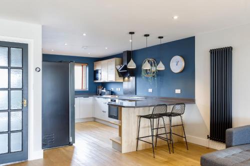 布莱顿霍夫Stylish & modern 4-bedroom home with sea views的厨房设有蓝色的墙壁和2个酒吧凳子