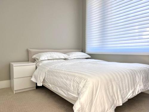 温哥华Brand New Modern Laneway House的卧室内的一张白色床,设有窗户