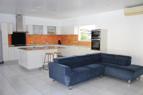 Rémire-CampVilla Émeraude - Piscine privée sans vis à vis的客厅设有蓝色沙发,厨房设有