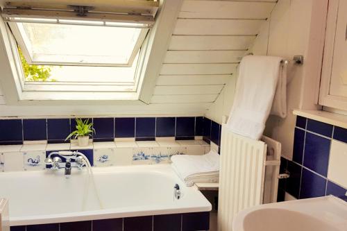 巴勒哈姆斯泰德Countryside Bliss: Historic Cottage by the Sea的带浴缸、水槽和窗户的浴室