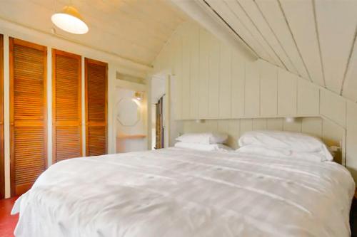巴勒哈姆斯泰德Countryside Bliss: Historic Cottage by the Sea的卧室铺有木地板,配有一张大白色床。