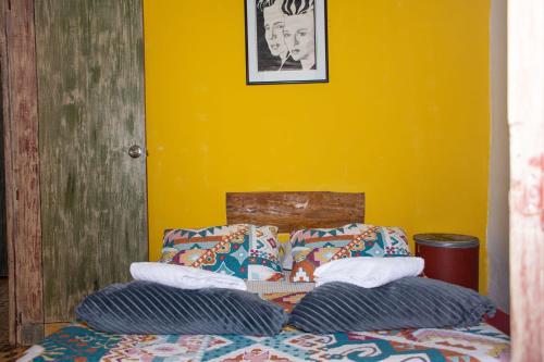 Carmen de ViboralHostal Macondo Inn的一张带两个枕头和黄色墙壁的床