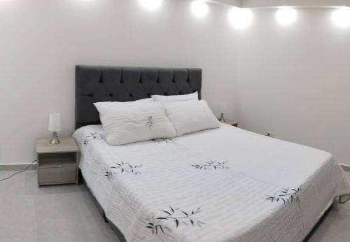 内瓦Encantador Apto Con Aire的一间卧室配有一张白色的床和黑色床头板