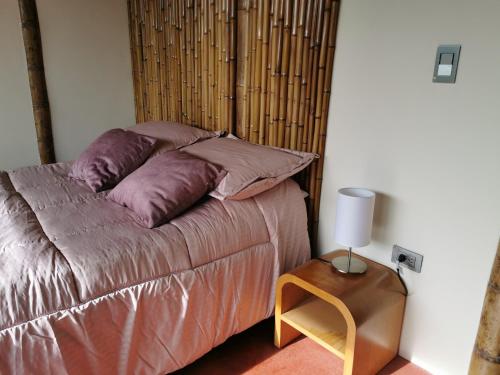 萨兰托Casa Tien的一张带紫色枕头的床和一张带台灯的桌子