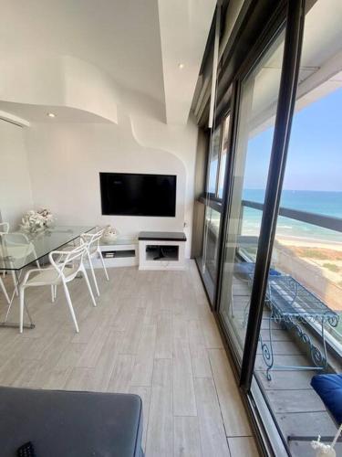 荷兹利亚Bruth’s balcony sea view apt的一间带桌子和电视的客厅,享有海景。