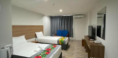 南迪Vualiku Hotel & Apartments的酒店客房设有两张床和电视。