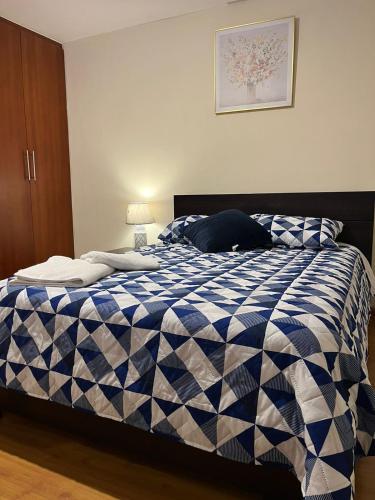 昆卡Departamento de 2 Habitaciones, full amoblada con todo para que disfrutes de tu Estancia的卧室内的一张蓝色和白色的床
