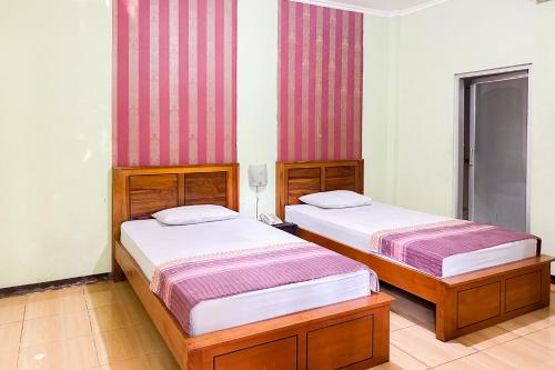Global Inn Syariah Mitra RedDoorz near Juanda T1 Airport的红色和白色条纹间内的两张床