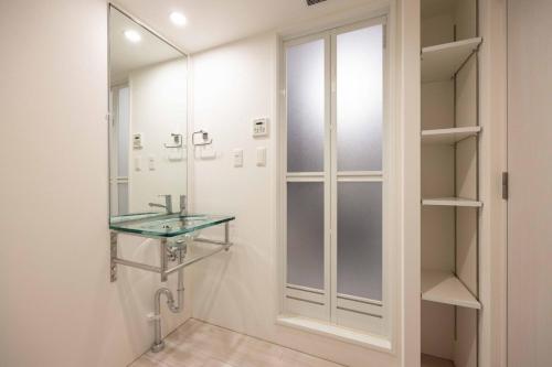东京Quador Waseda的一间带玻璃水槽和镜子的浴室