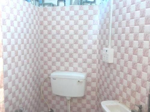 加尔各答Venus Homestay的一间带卫生间的浴室和粉红色的格子墙
