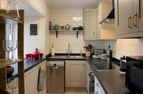 StrathdonSmithy Cottage的厨房配有白色橱柜和水槽