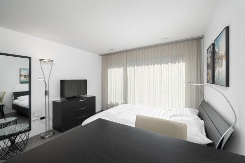 因特拉肯Studio NATASCHA Interlaken的一间白色卧室,配有床和电视