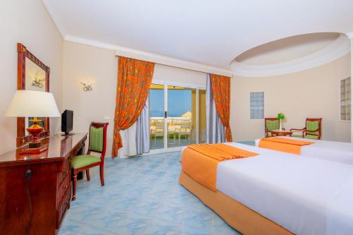 赫尔格达Siva Golden Bay Makadi的酒店客房设有两张床、一张桌子和一台电视。