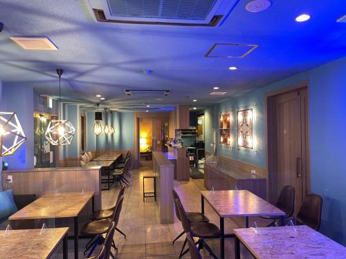 泉佐野海鸥酒店的餐厅设有木桌和椅子,灯光蓝色