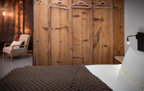 La SagneHôtel-Restaurant Le Cochon Rose的一间卧室设有木墙、一张床和一把椅子