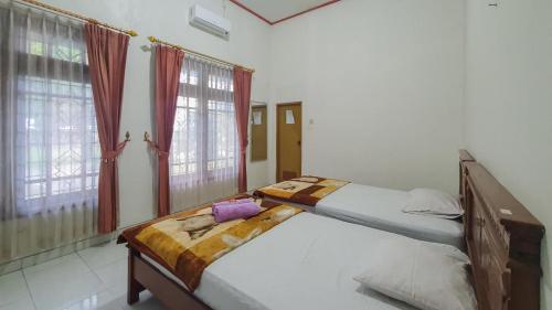 外南梦Villa Pakis Residence Banyuwangi的卧室内的两张床,配有红色窗帘