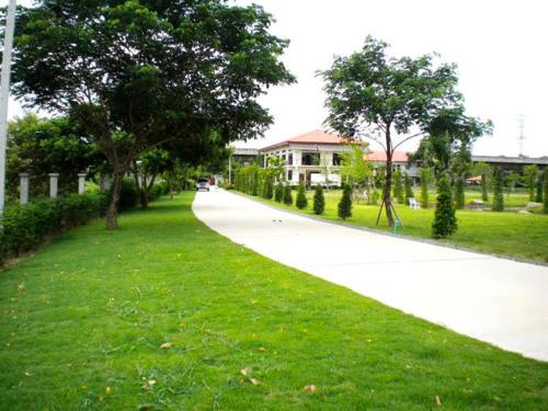 巴吞他尼Sripiamsuk Resort Bangkok的公园里树木和草地的步行路径