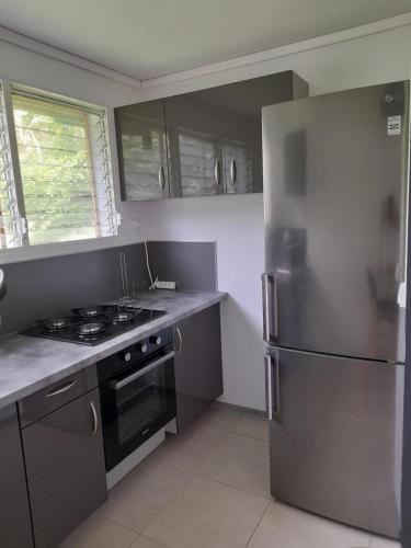 法兰西堡T2 Bambou的厨房配有不锈钢冰箱和炉灶。