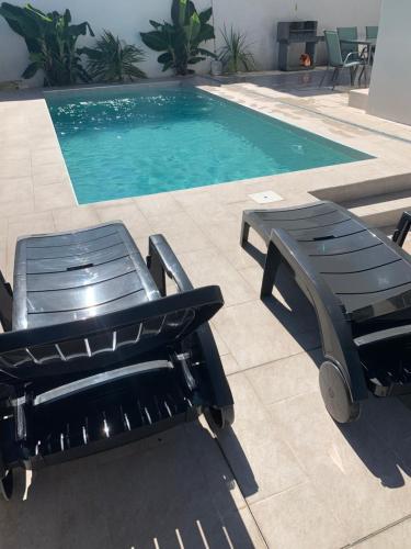 艾姆布里亚布拉瓦Maison Bella的游泳池旁设有两把椅子和长凳
